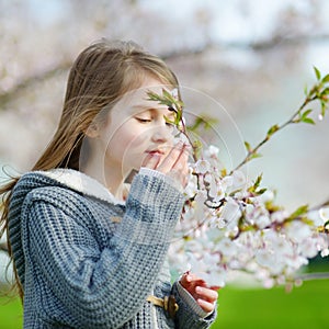 Adorable little girl in blooming cherry garden