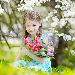 Adorable little girl in blooming cherry garden