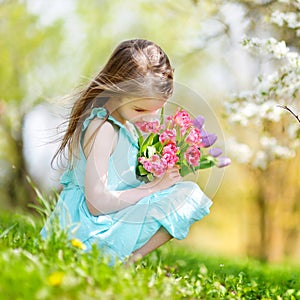 Adorable little girl in blooming cherry garden