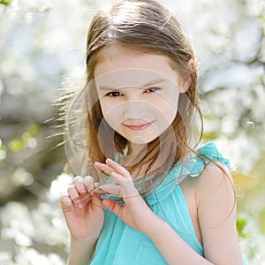 Adorable little girl in blooming cherry garden