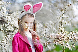 Adorable little girl in blooming cherry garden