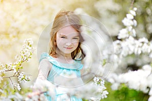 Adorable little girl in blooming cherry garden