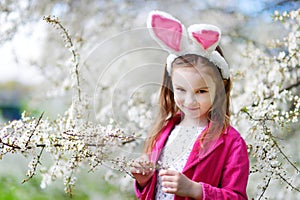 Adorable little girl in blooming cherry garden