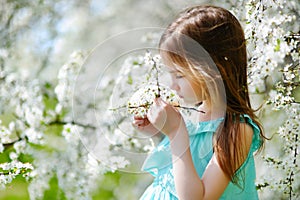 Adorable little girl in blooming cherry garden