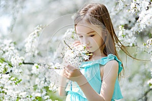 Adorable little girl in blooming cherry garden