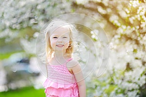 Adorable little girl in blooming cherry garden