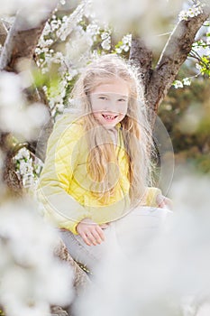 Adorable little girl in blooming cherry tree garden