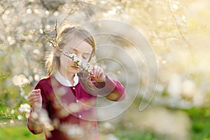 Adorable little girl in blooming cherry tree garden on beautiful spring day