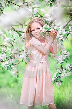 Adorable little girl in blooming cherry tree garden outdoors