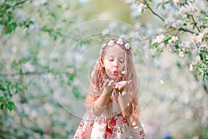 Adorable little girl in blooming cherry tree garden on spring day