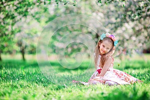 Adorable little girl in blooming cherry tree garden on spring day