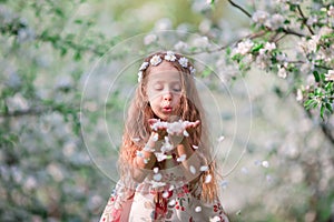 Adorable little girl in blooming cherry tree garden on spring day