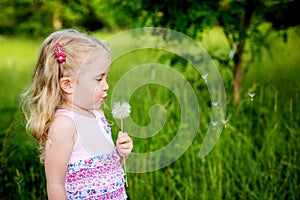 Adorable little girl blowing off dandelion