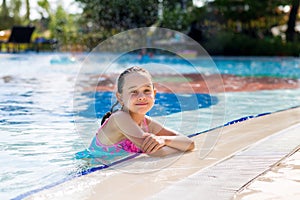 Adorable little girl in bright swimsuit in swimming pool on vacation on sunny summer day. Family vacation concept