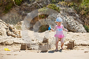 Adorable little girl building sand castles on beach
