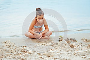 Adorable little girl building a sandcastlle at the seashore