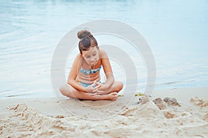 Adorable little girl building a sandcastlle at the seashore