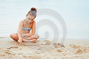 Adorable little girl building a sandcastlle at the seashore