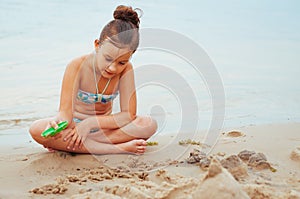 Adorable little girl building a sandcastlle at the seashore