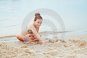 Adorable little girl building a sandcastlle at the seashore