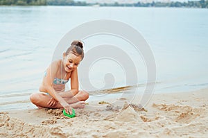 Adorable little girl building a sandcastlle at the seashore