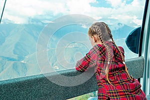 Adorable little girl in the cabin on the cable car in mountains