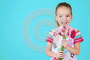 Adorable little girl with cheeky smile and face expression holding bouquet of pink gerbera daisies. Happy Mother`s Day.