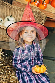 Adorable little girl choosing halloween pumpkin