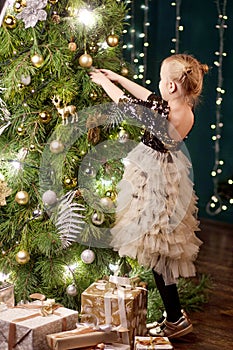 Adorable little girl  Christmas tree at home. Cute kid preparing home for xmas celebration. Christmas and New Year celebration