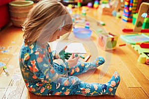 Adorable little girl drawing with green felt pen on her palm