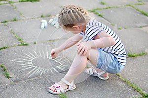 Adorable little girl drawing outside with chalk