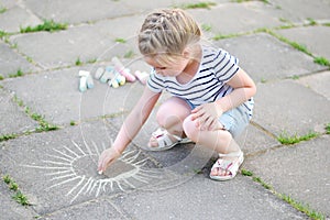 Adorable little girl drawing outside with chalk