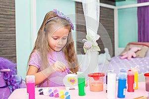 Adorable Little girl draws paints at her table in