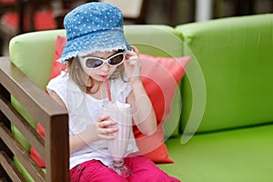 Adorable little girl drinking milkshake