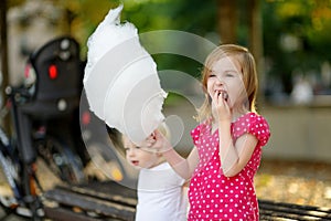 Adorable little girl eating candy-floss outdoors