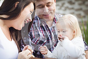 Adorable Little Girl Eating a Cookie with Mommy and Daddy