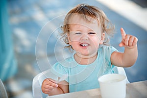 Adorable little girl eating ice cream at outdoor cafe