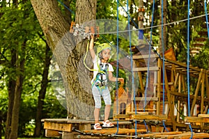 Adorable little girl enjoying her time in climbing adventure park on warm and sunny summer day