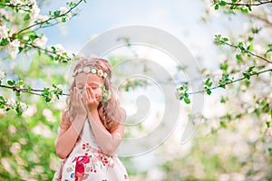 Adorable little girl enjoying smell in a flowering cherry spring garden