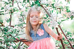 Adorable little girl enjoying spring day in apple blooming garden