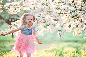 Adorable little girl enjoying spring day in apple blooming garden