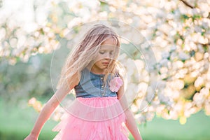 Adorable little girl enjoying spring day in apple blooming garden