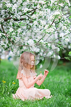 Adorable little girl enjoying spring day in apple blooming garden