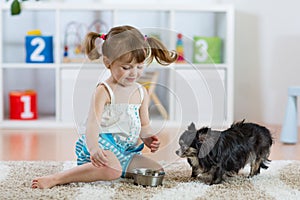 Adorable little girl feeding cute dog