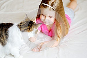 Adorable little girl feeding her cat