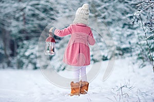 Adorable little girl with flashlight and candle in winter