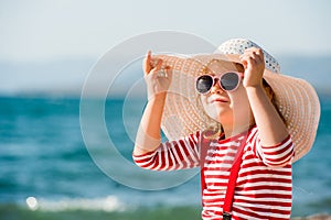 Adorable little girl in hat and sunglasses at beach on summer vacation