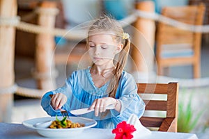 Adorable little girl having dinner at outdoor cafe