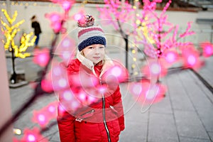 Adorable little girl having fun on beautiful Christmas time. Cute child having a walk in winter town.