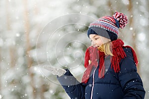 Adorable little girl having fun in beautiful winter park. Cute child playing in a snow.